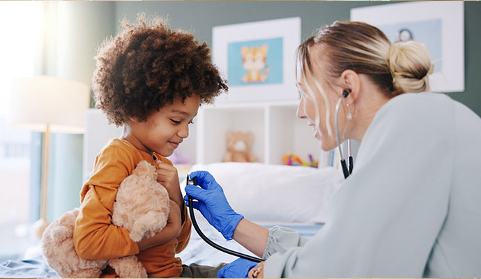 Friendly pediatrician examining young boy with stethoscope
