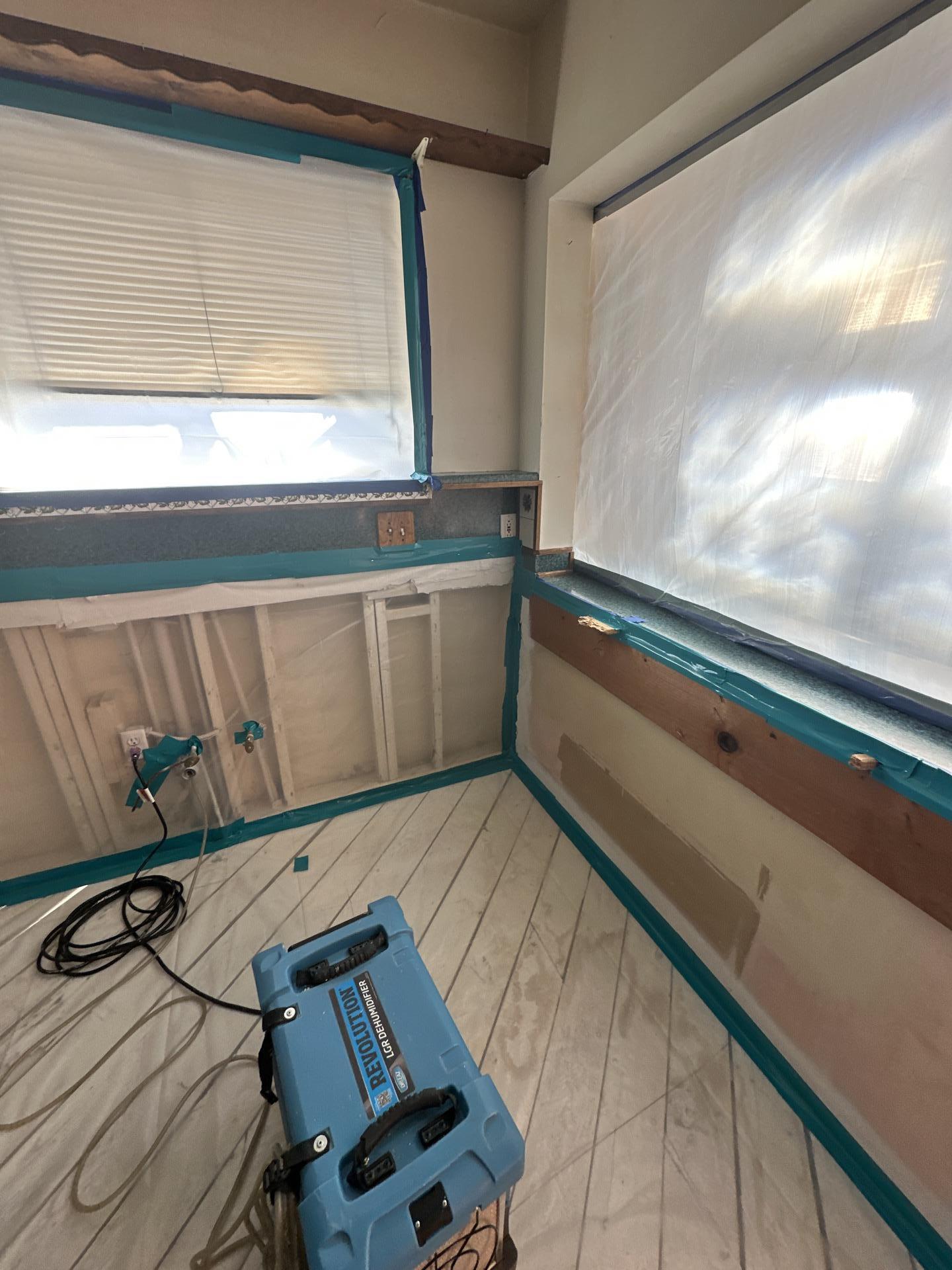 Water mitigation in progress showing professional structural drying and dehumidification equipment operating within a containment area, targeting hidden water damage in wall cavities near windows.