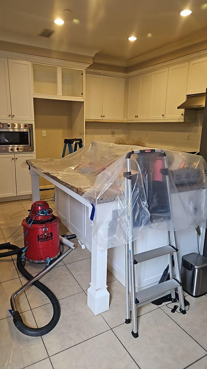 Kitchen restoration in progress after a shower leak, showing countertops protected and a HEPA vacuum used for cleanup during water mitigation and structural repair services.