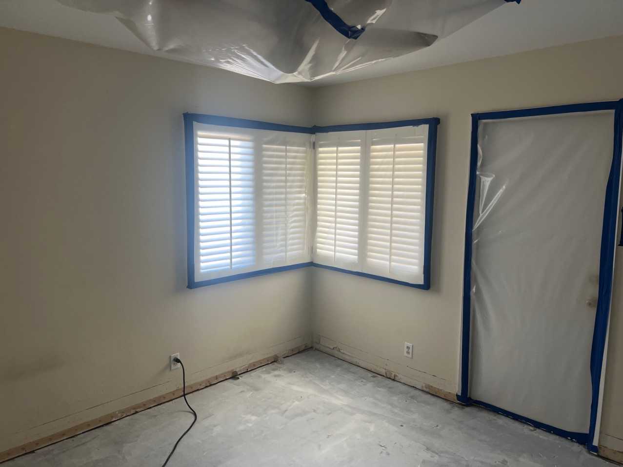 Reconstruction phase showing bedroom prepared for restoration, with drywall removed at the base, door sealed, and vinyl plank flooring area cleared, ready for structural repair and refinishing.