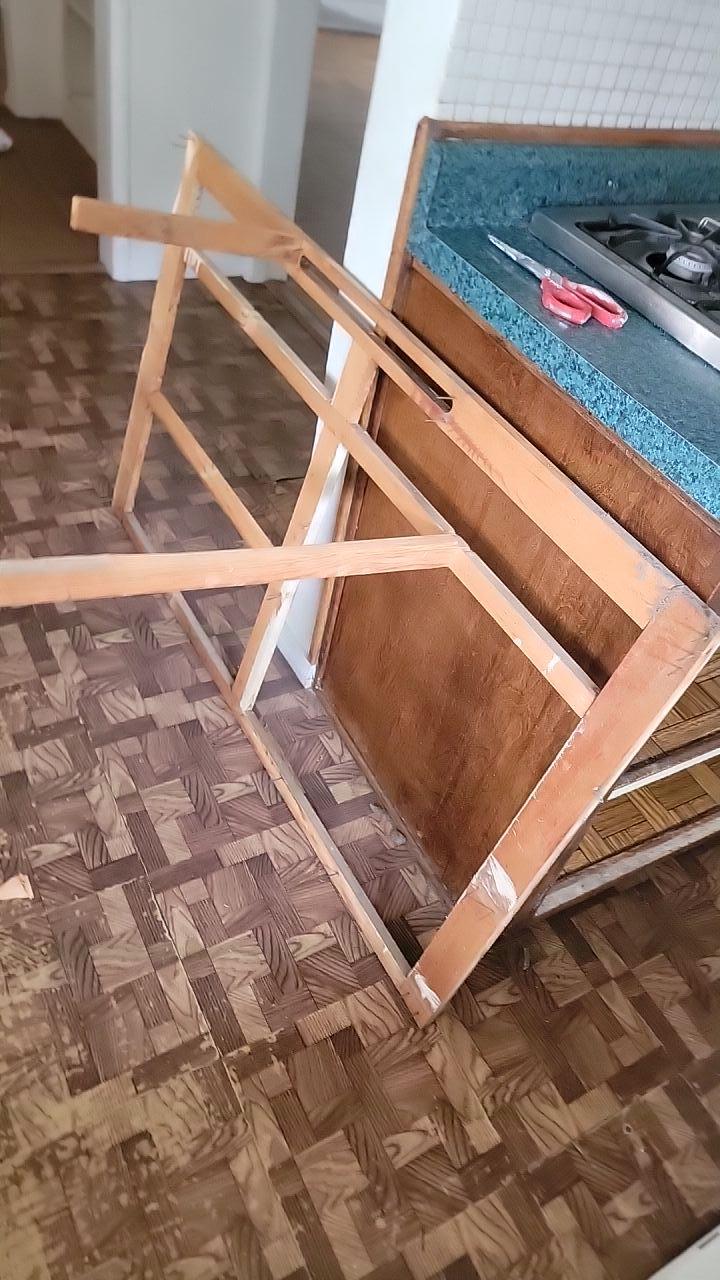 Water damage mitigation in the kitchen/dining area, showing removal of cabinet toe kicks for access to wet areas and effective structural drying and water extraction to protect the flooring.