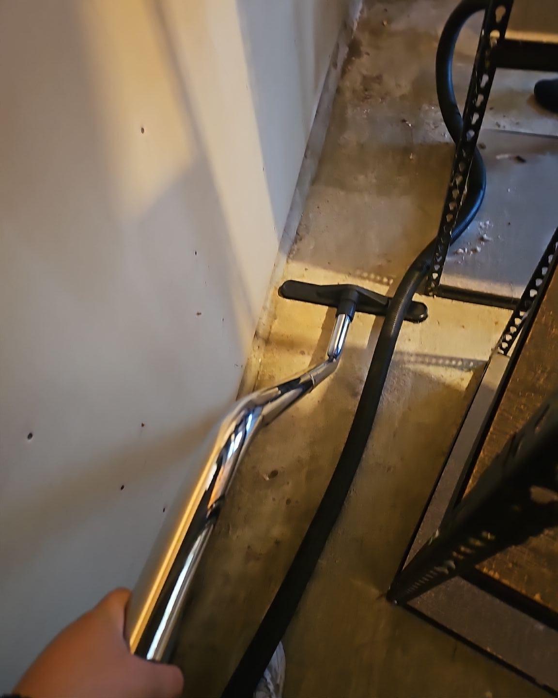 Emergency fire damage mitigation in a storage room, showing professional vacuum equipment performing detailed soot cleanup and smoke removal from floors and baseboards for full property restoration.