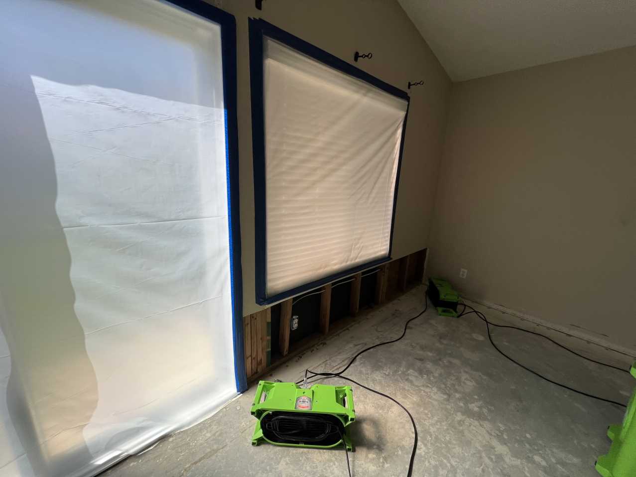 Water mitigation in progress showing structural drying equipment and containment barriers set up in the master bedroom to address water damage in the wall cavity and prevent mold growth.