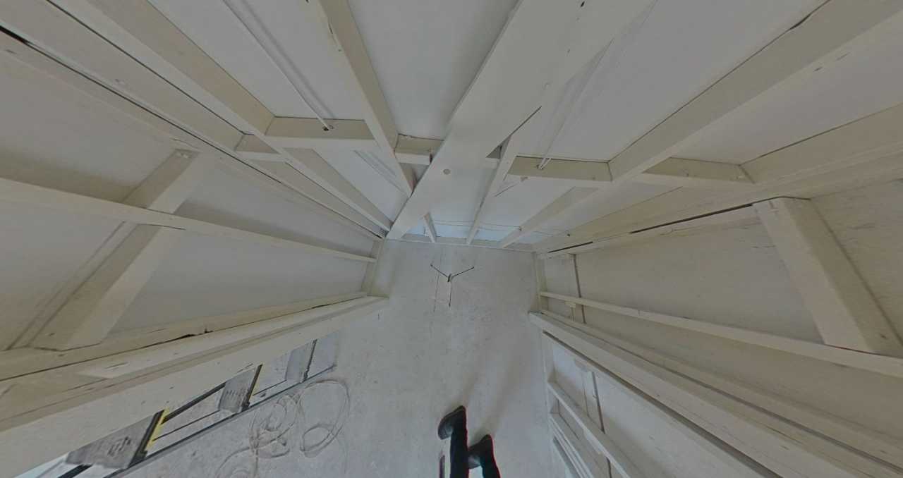 Fire damage mitigation showing exposed ceiling and wall structure in a bedroom, critical for assessing full extent of damage and performing complete smoke and soot removal during property restoration.