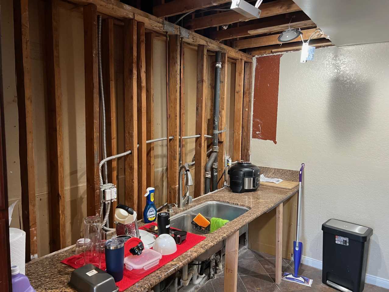 A kitchen in the midst of professional water damage demolition, with damaged drywall and upper cabinets removed. Our team carefully performs this vital step to prepare the area for repair and ensure complete property restoration after an incident