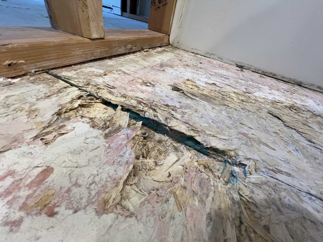 A close-up of a severely water-damaged subfloor, a result of a ruptured attic pipe. This photo shows the type of structural damage that requires professional water damage restoration, including the removal of compromised materials and a thorough drying process before reconstruction.