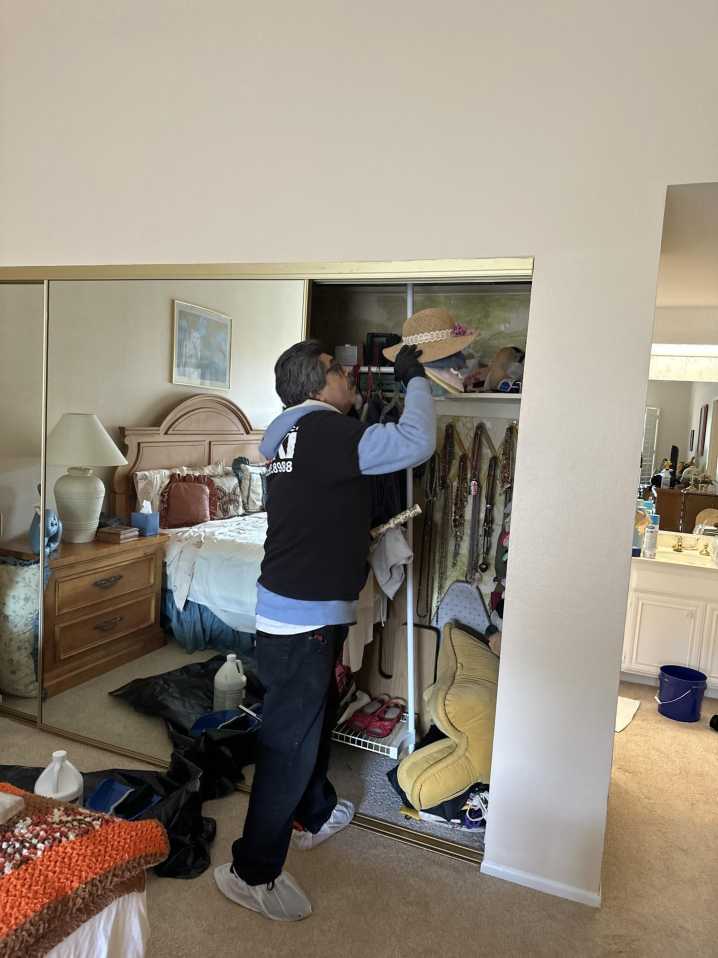 A technician carefully handles personal belongings inside a bedroom closet as part of a comprehensive fire damage cleanup. Our team specializes in contents restoration, ensuring all items affected by smoke damage are meticulously cleaned and restored