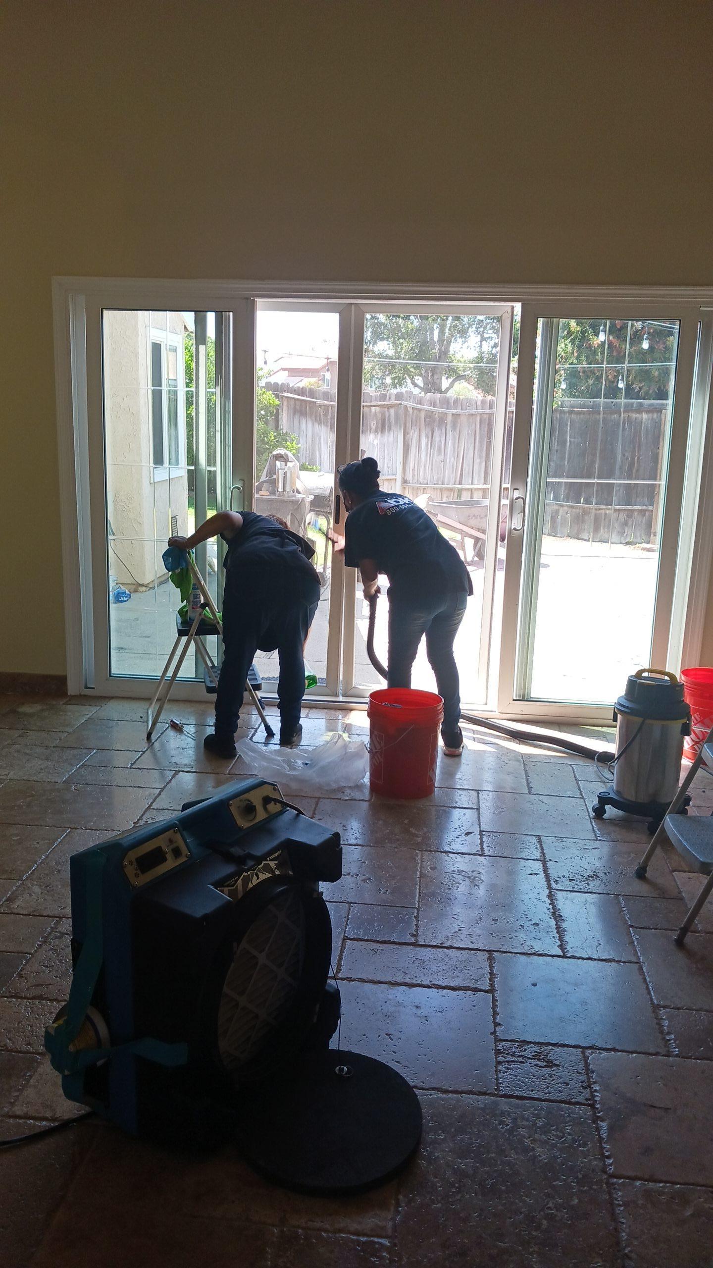 Technicians performing water extraction and structural drying using air movers after fire sprinkler activation, crucial for combined fire and water damage mitigation and floor property restoration.