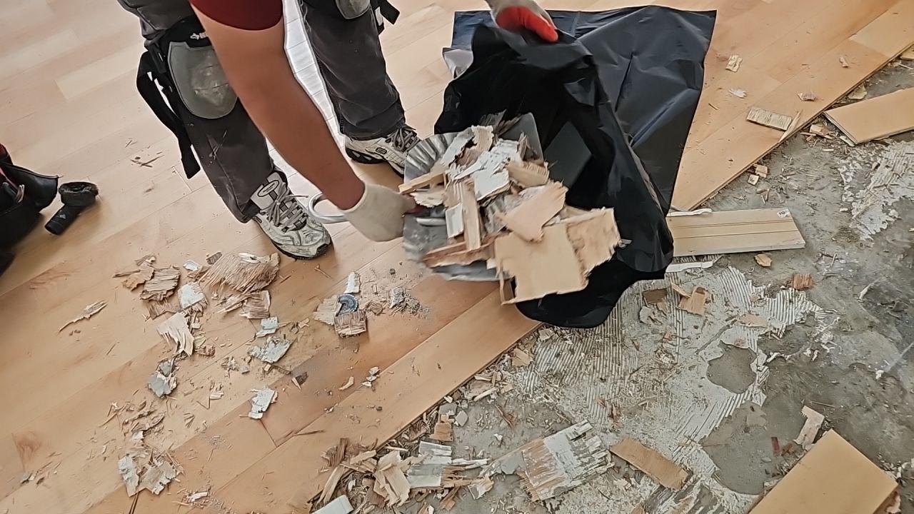 A technician sweeps up and removes debris after a water leak repair. This professional water damage cleanup ensures the workspace is clean and safe, a crucial step before full property restoration.