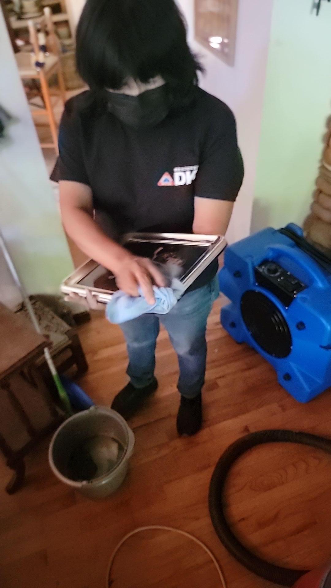 Technician performing detailed contents cleaning to remove soot and smoke residue from salvaged items, a vital part of emergency fire damage mitigation and overall property restoration.