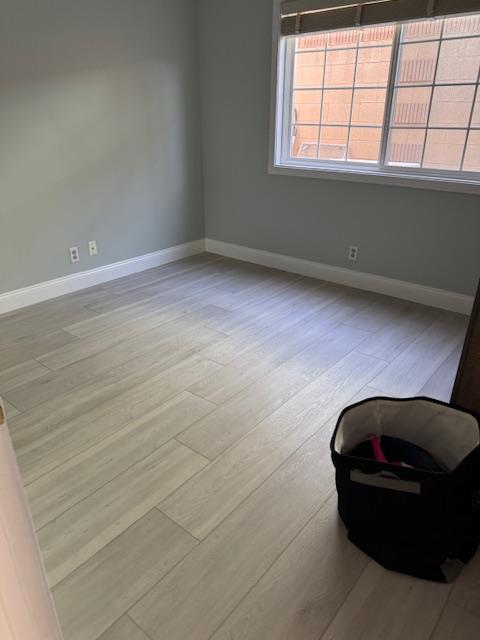 Final property reconstruction of a bedroom, featuring newly installed vinyl plank flooring, fresh paint, and baseboards, completing the structural repair and restoration to pre-loss condition.