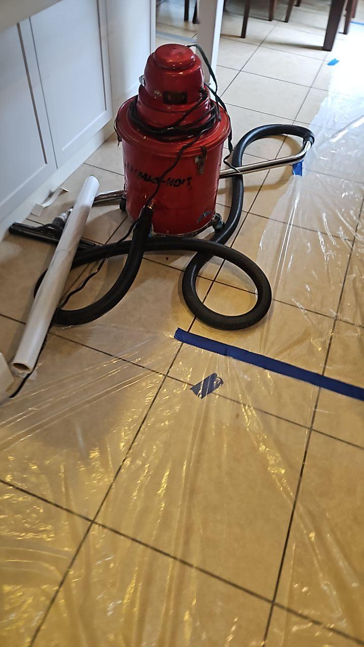 HEPA vacuum and plastic sheeting used for dust and debris containment during water damage mitigation after a plumbing leak, ensuring clean kitchen restoration and proper cleanup procedures.