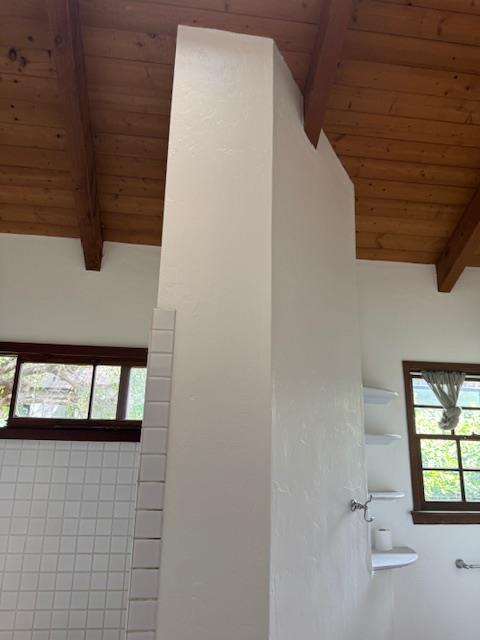 Smoke damage restoration in a bathroom, showing cleaned walls, tile, and restored vaulted wood ceiling, demonstrating professional soot cleanup and successful odor removal services.