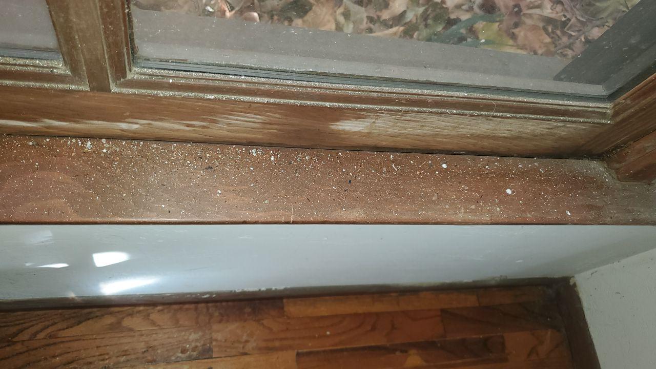 Close-up of soot and smoke residue accumulation on a window sill, requiring detailed smoke damage cleanup and odor deodorization as part of emergency fire damage mitigation services.