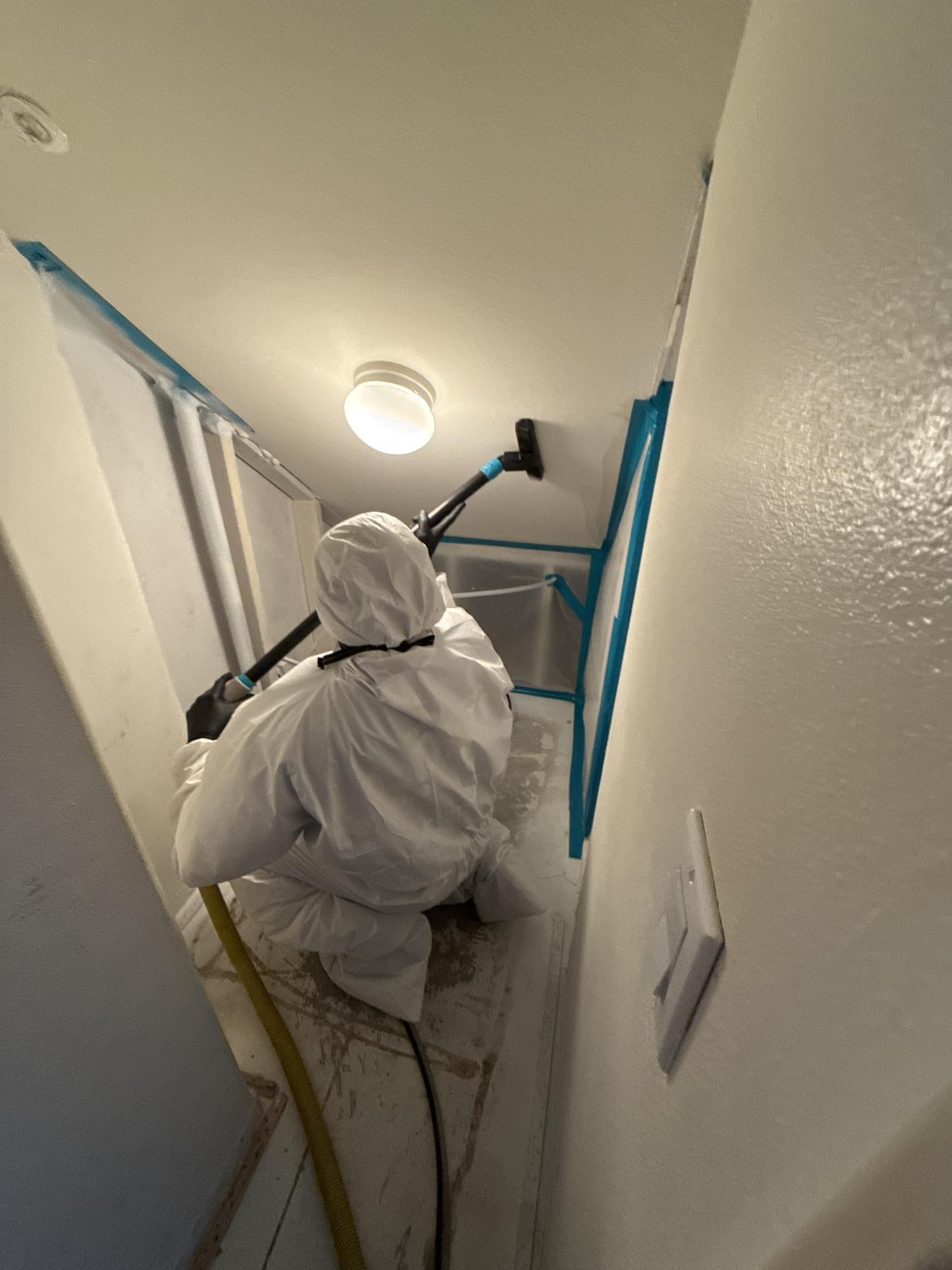 Water mitigation in progress: Technician in full PPE performing detailed cleaning and high-vacuum water extraction in a tight space to ensure all moisture is removed and prevent mold growth following water intrusion.