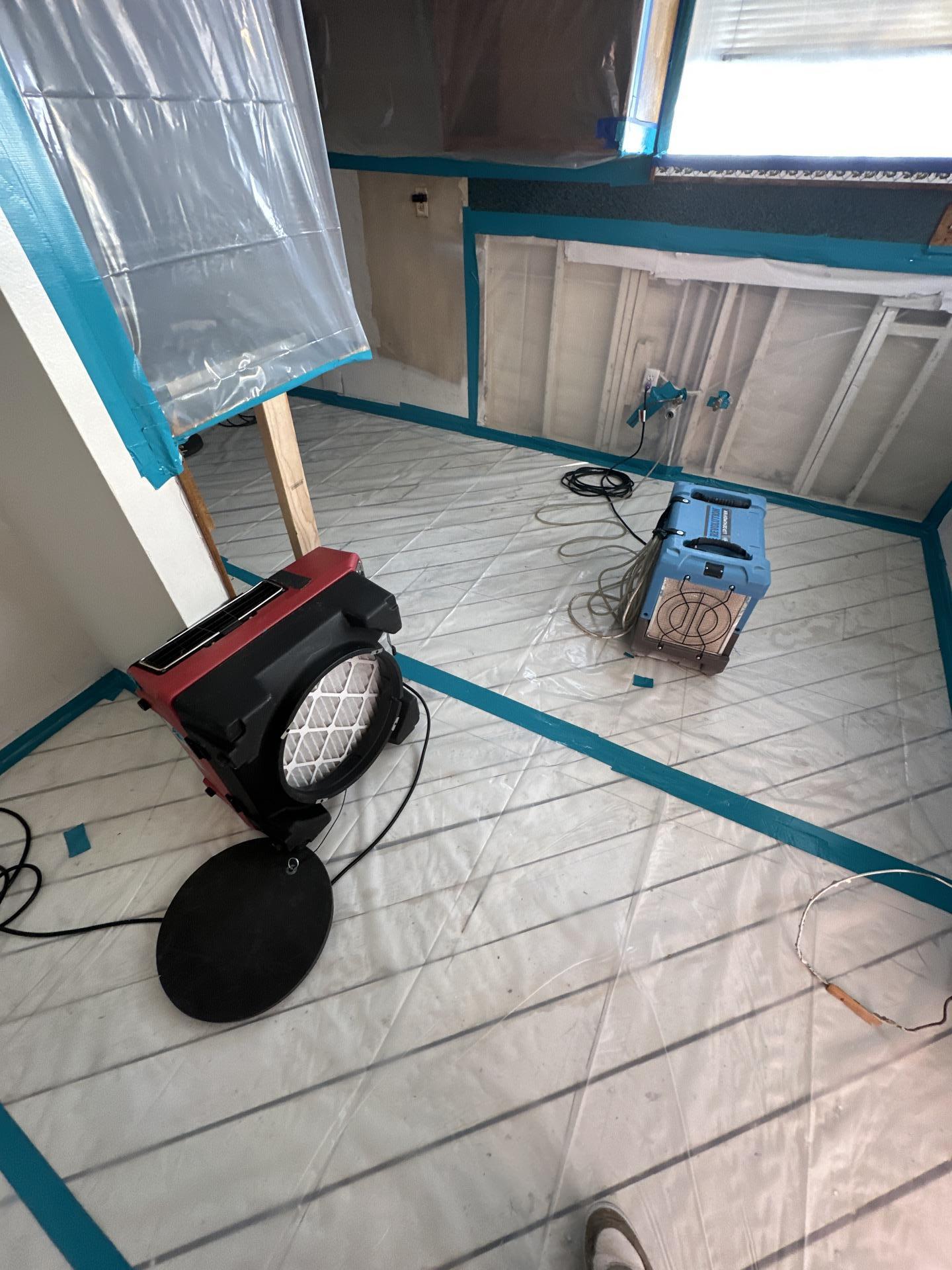 Advanced water damage restoration setup with containment barriers, air movers, and dehumidifiers actively performing structural drying and dehumidification to prevent mold growth and restore the property.
