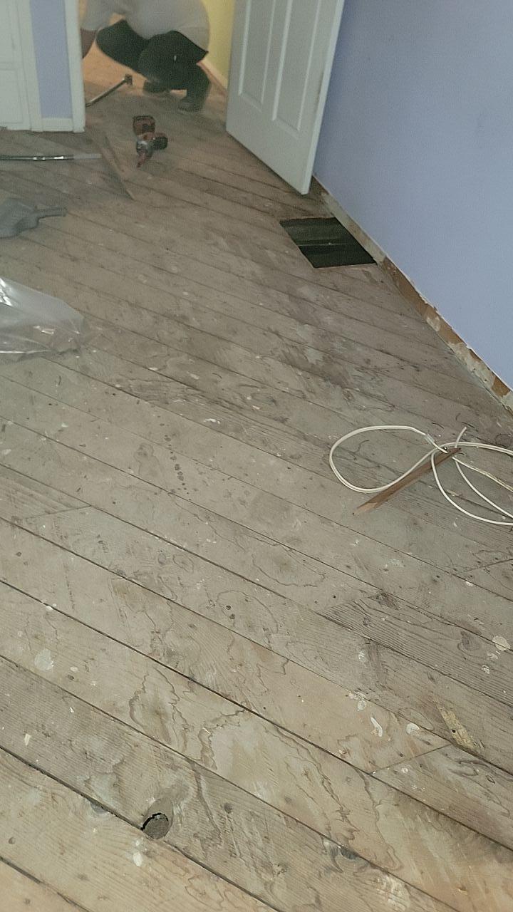 Emergency fire damage mitigation showing exposed wood subfloor after debris removal and removal of damaged carpet/flooring, preparing the area for structural drying and full property restoration.