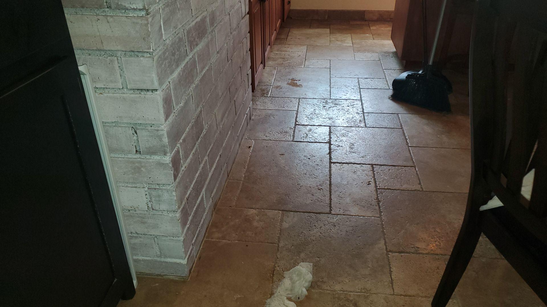 Kitchen floor cleanup showing heavy soot and smoke residue on tile and brick surfaces, requiring professional fire damage mitigation and water damage restoration to clean and deodorize the property.